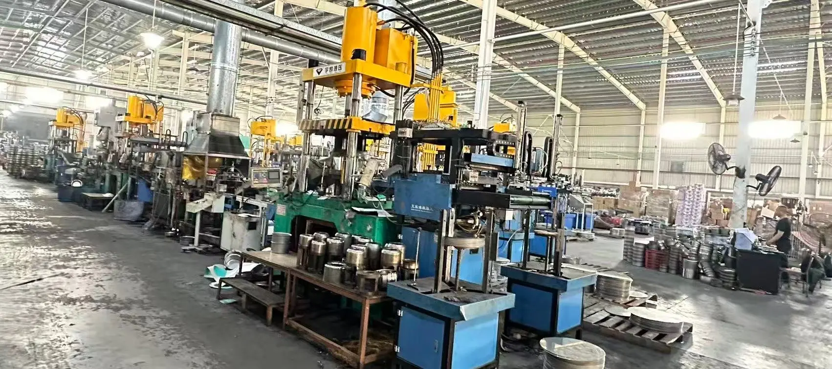 stainless steel cookware manufacturing factory floor with hydraulic presses