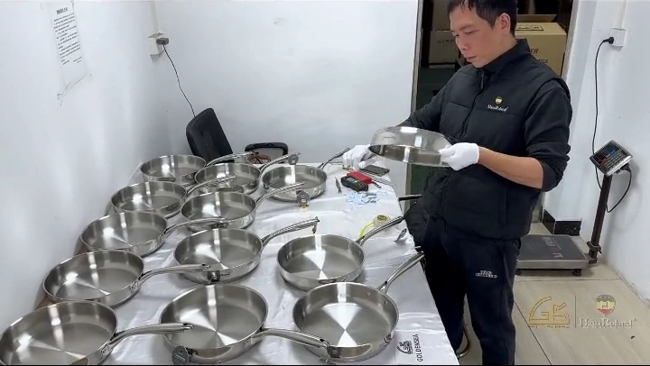 Stainless steel frying-pan samples under visual quality inspection before bulk production