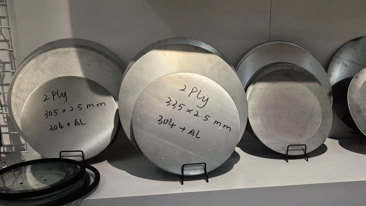 Circular cookware blank samples showing stainless steel and aluminum constructions