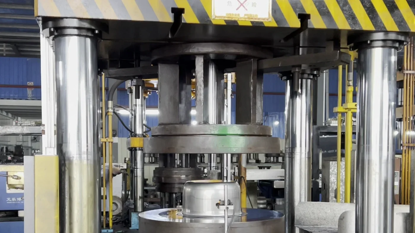 Stainless steel cookware body undergoing deep drawing in a forming press