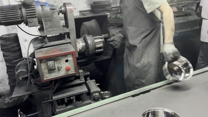 Cookware finishing and assembly: worker operating pot-body polishing equipment